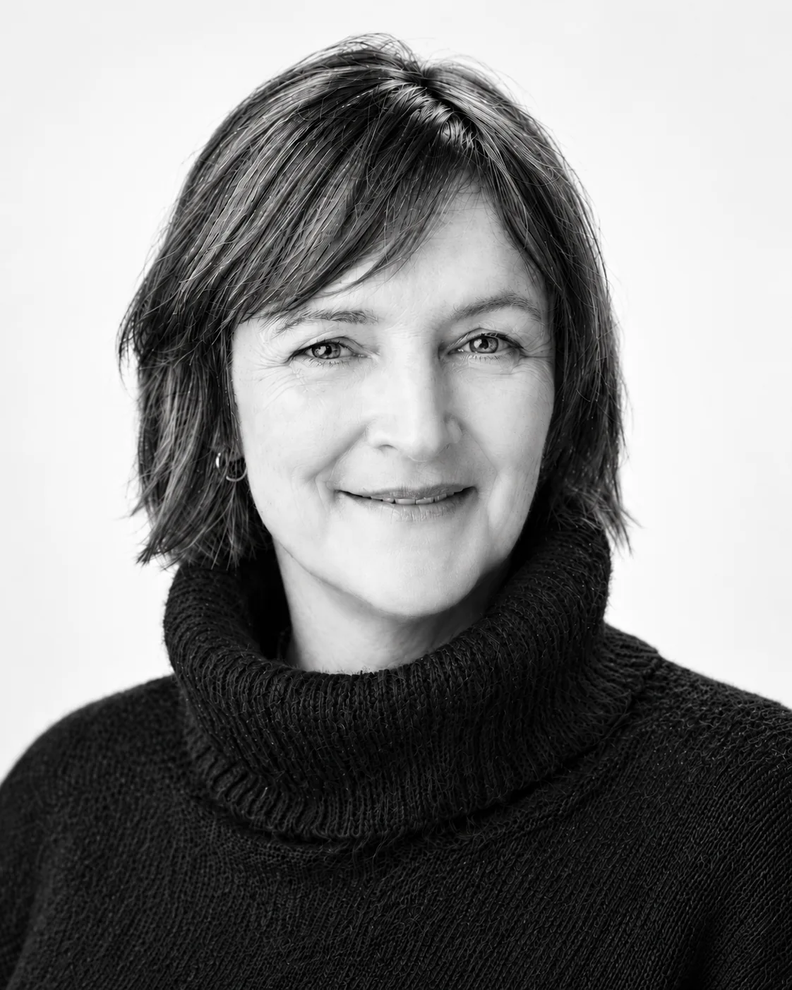 Zwart-witportret van Emilie van Rappard: lachende vrouw met kort haar en een zwarte coltrui, tegen een lichte achtergrond.